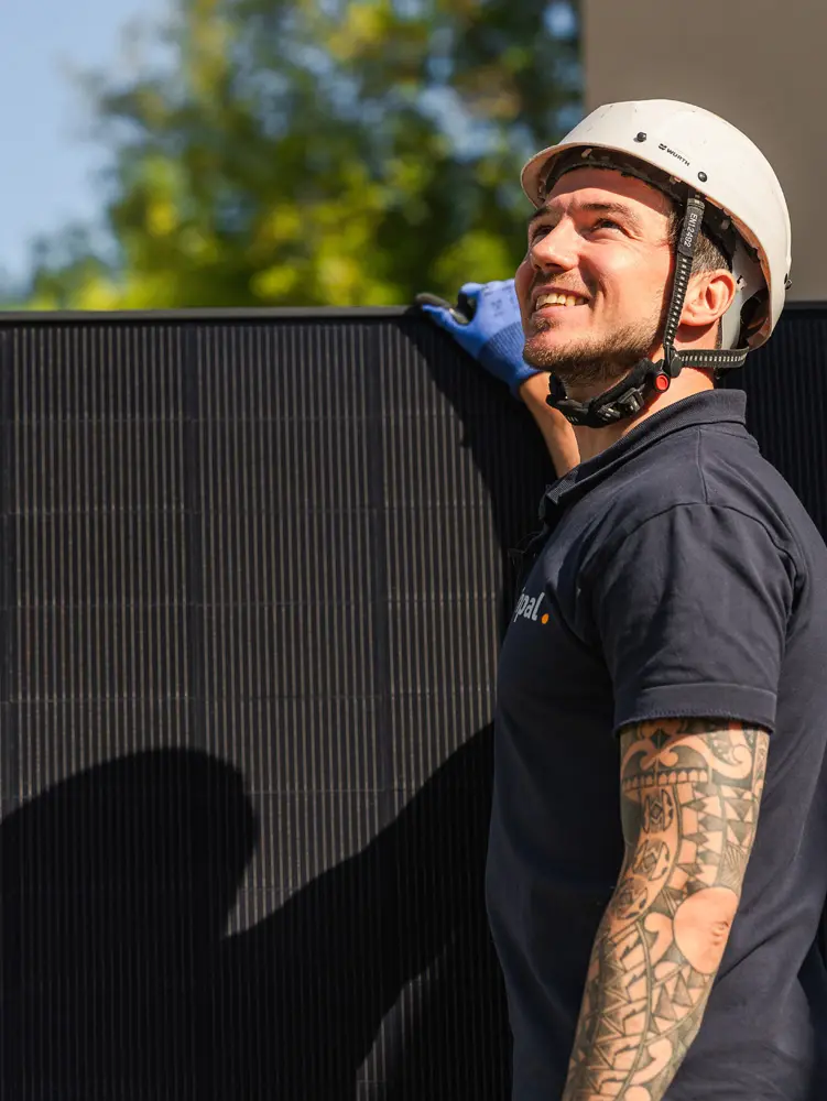 Infravoltaic-Monteur mit Solarmodul blickt hoch aufs Dach